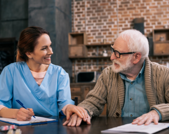 caregiver holding a pen and elderly man smiling