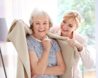 caregiver putting a blanket on the elderly