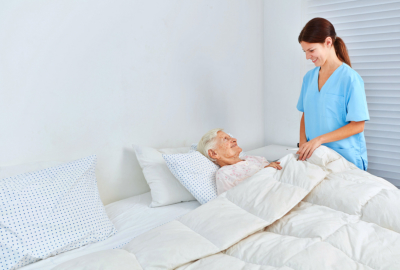 Caregiver assist elderly woman in bed